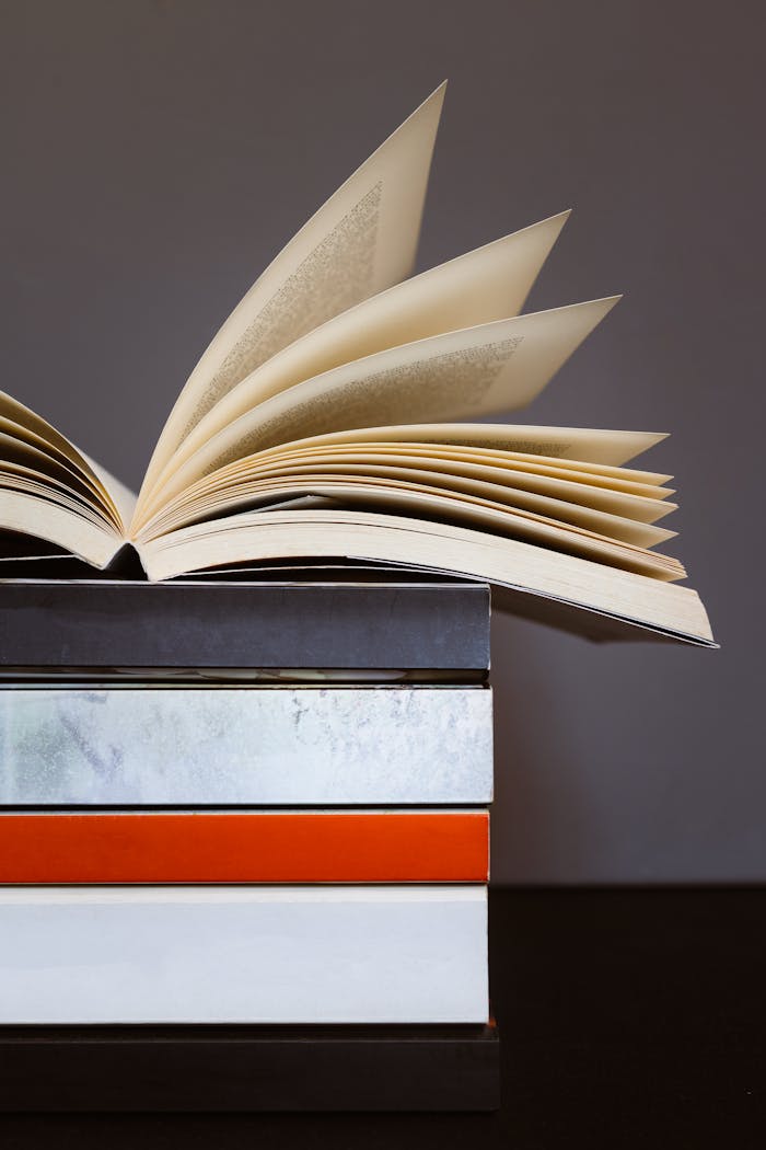 about-01 Creative photo of an open book on stacked colorful books, symbolizing learning and literature.